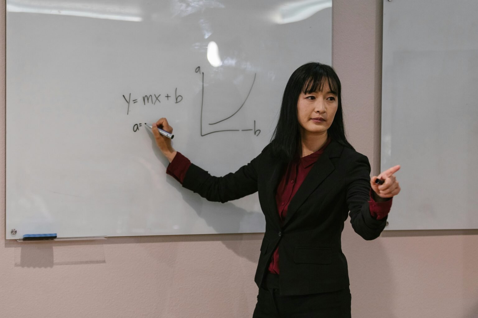 Une enseignante trace une courbe au tableau blanc