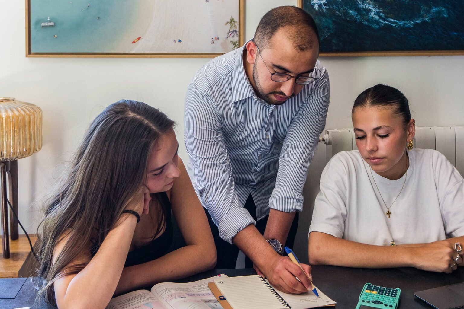 Un enseignant accompagne deux élèves pendant une séance de travail