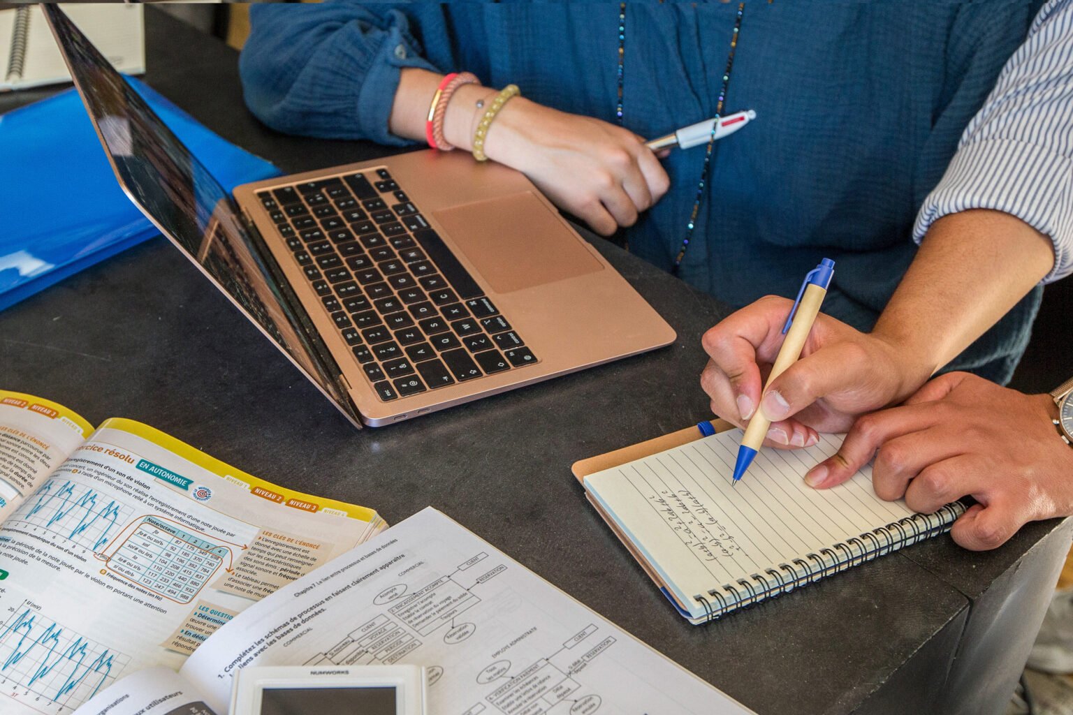 Un ordinateur portable et un carnet de notes posés sur une table de travail